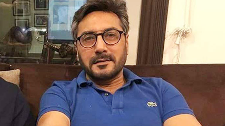 عدنان صدیقی کی سائن بورڈ  کے ساتھ تصویر پر بحث